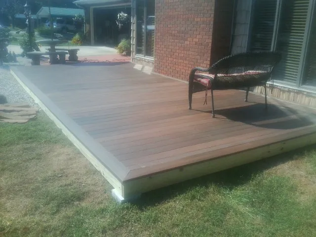 New wood deck and wicker chair beside a brick house in Lawrence Township