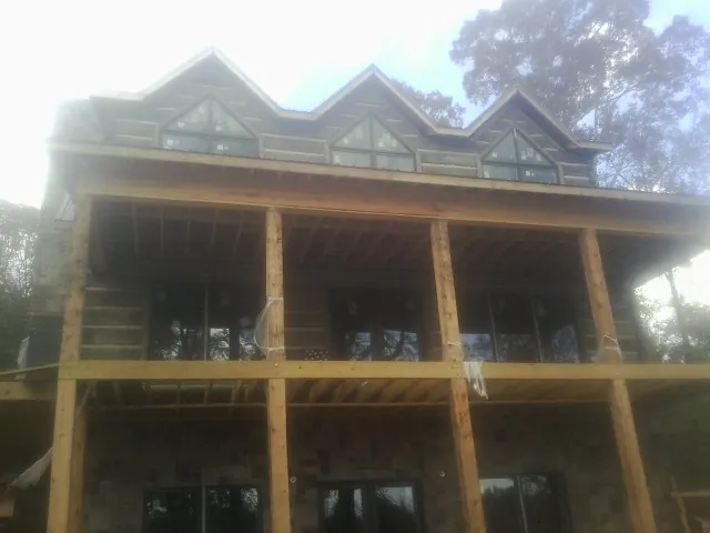 Dormers and porch framing on a large log home under construction — Roof Coating work by our crew in Lawrence Township