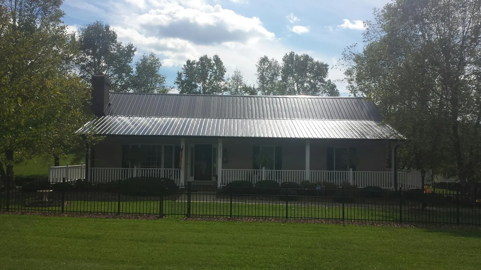Gray metal roof on a brick ranch with a full width front porch — Gutter Guard Installation work by our crew in Lawrence Township