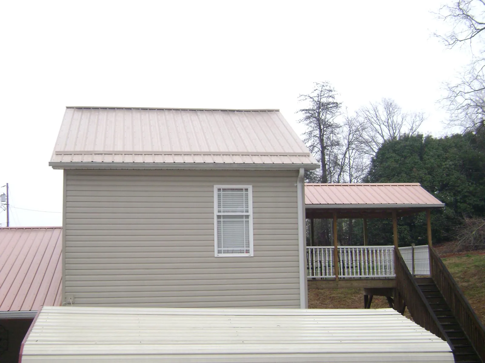 Tan metal roofs on a two story addition and attached porch, from a Roof Replacement job in Lawrence Township