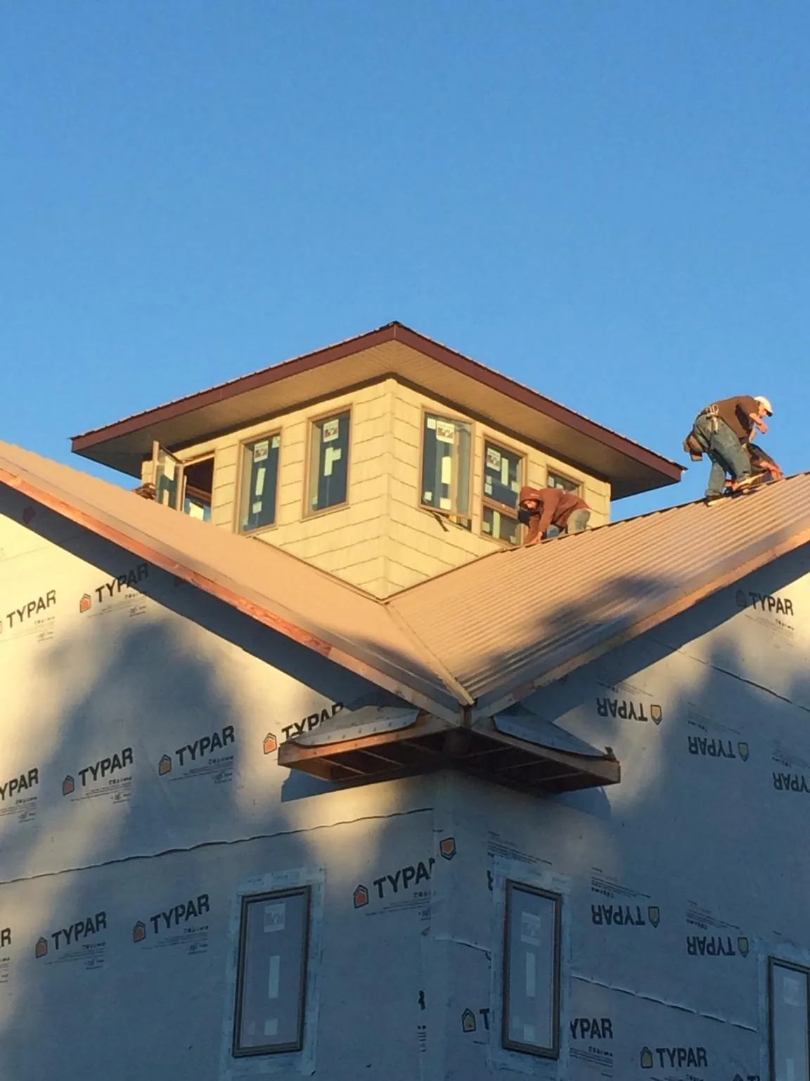 Roofers working around a rooftop cupola on a new metal roof at sunset — Roof Waterproofing in Lawrence Township by Roofing Brothers